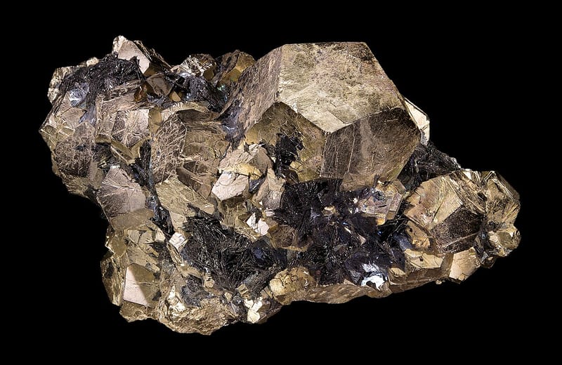 Kelompok kristal pirit mengilap dengan bidang bersegi pada latar hitam.